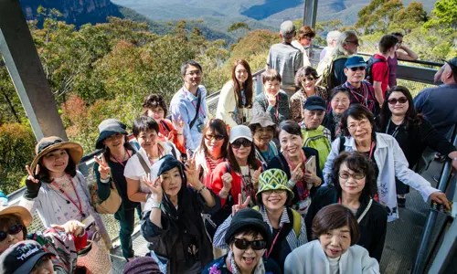 Smiling group of Japanese visitors take photo from Blue Mountains scenic view