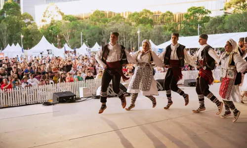 Serbian dancers onstage performing for an outdoor crowd at Serbian Festival