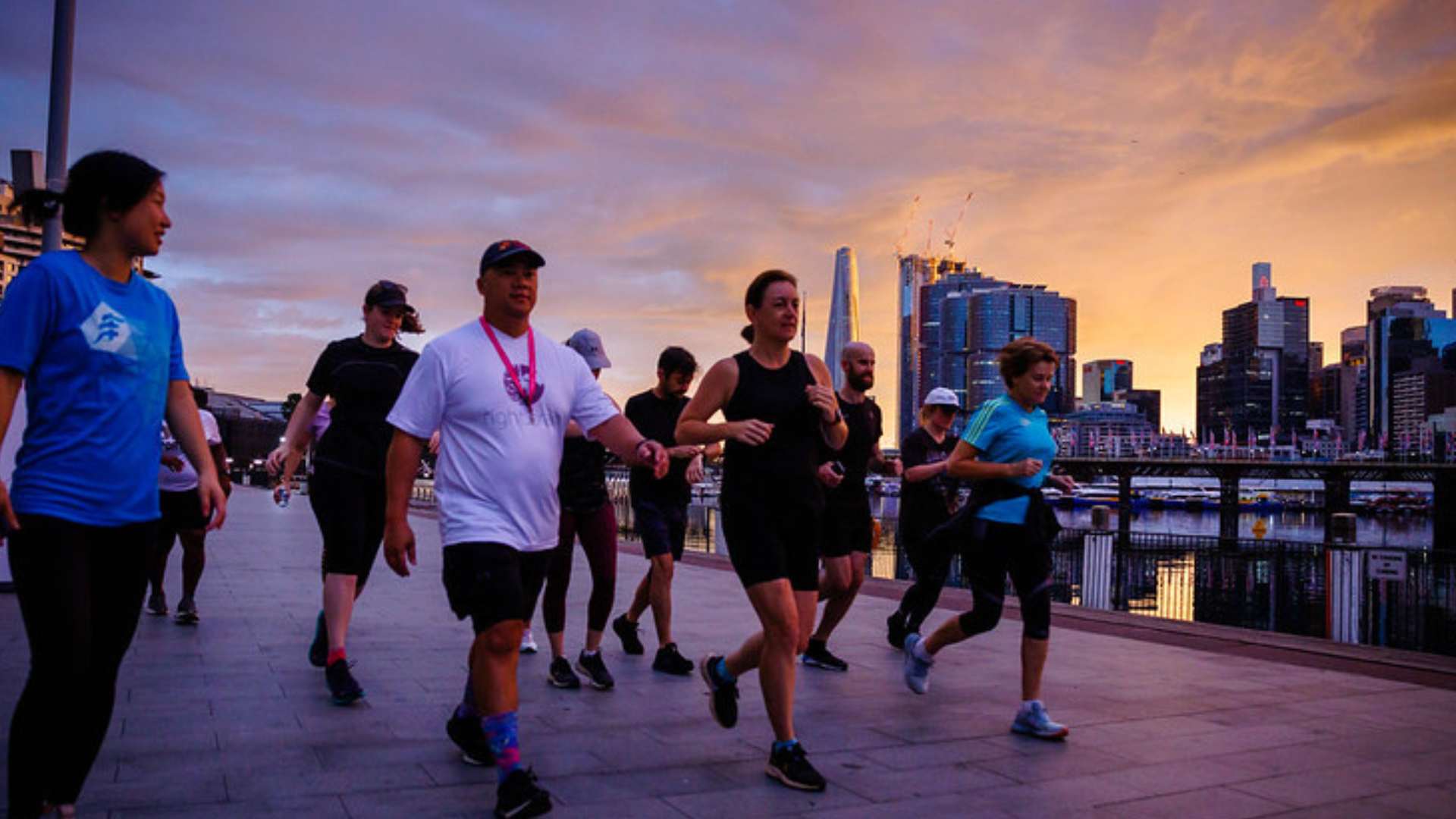 city walks with group of people running near the harbour at sunrise