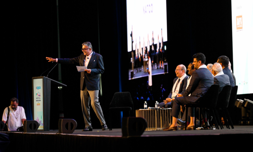 Panel of speakers on stage, smiling and looking at the delegate crowd
