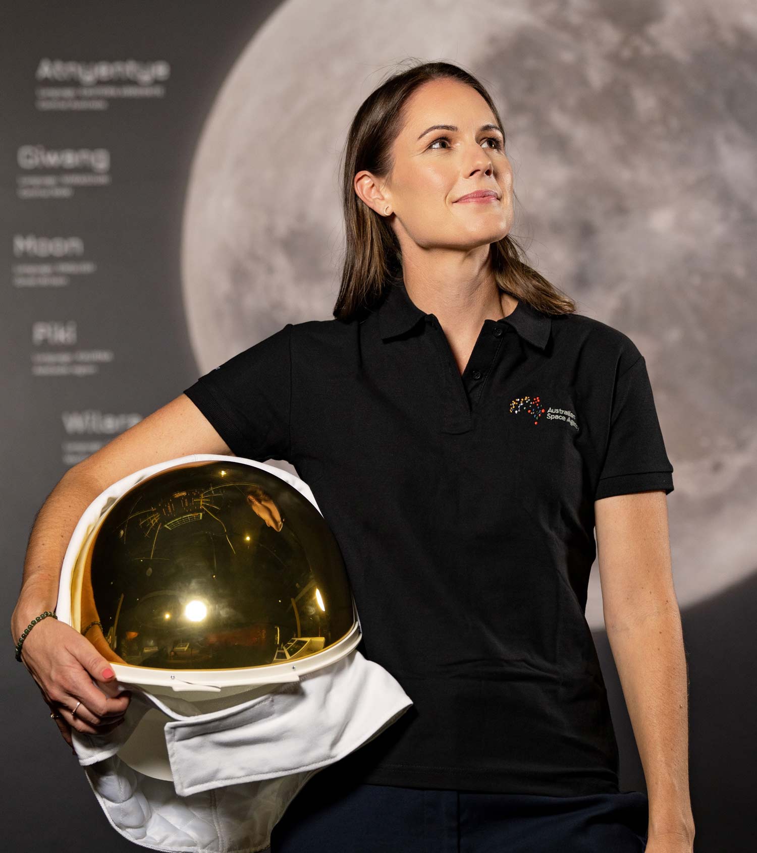Professional headshot of Australian astronaut Katherine Bennell-Pegg, standing with her space helmet and looking up