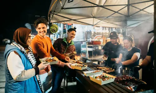 A group enjoys skewers from a food stall at Lakemba